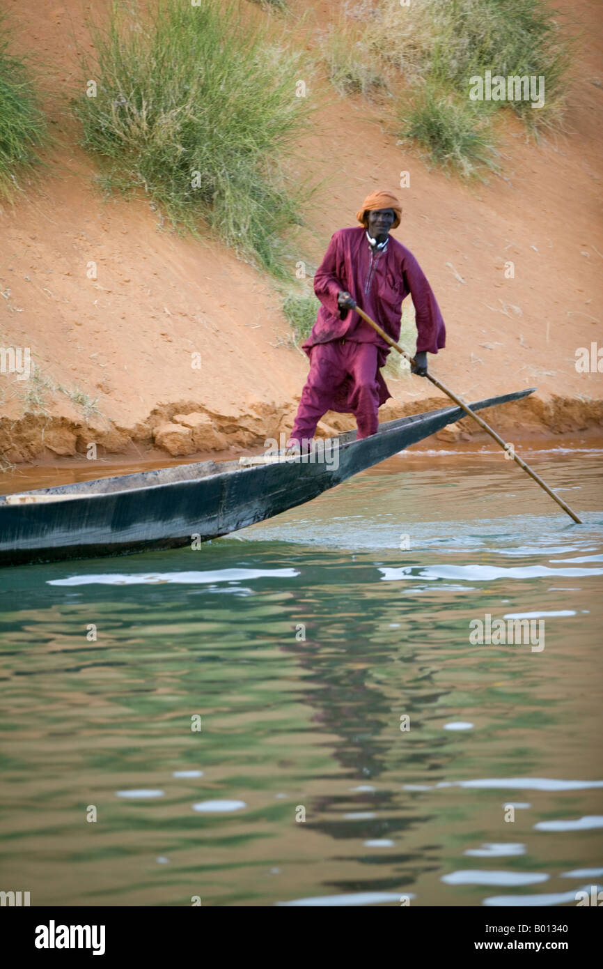 Mali, Gao. Ein Mann in bunten muslimische Kleidung Polen seine Holzboot auf dem Niger in der Nähe von Gao. Stockfoto