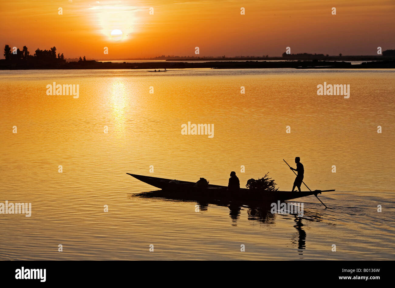 Mali, Mopti. Bei Sonnenuntergang Fähren ein Fährmann in einer Piroge Passagiere über den Fluss Niger, Mopti. Stockfoto