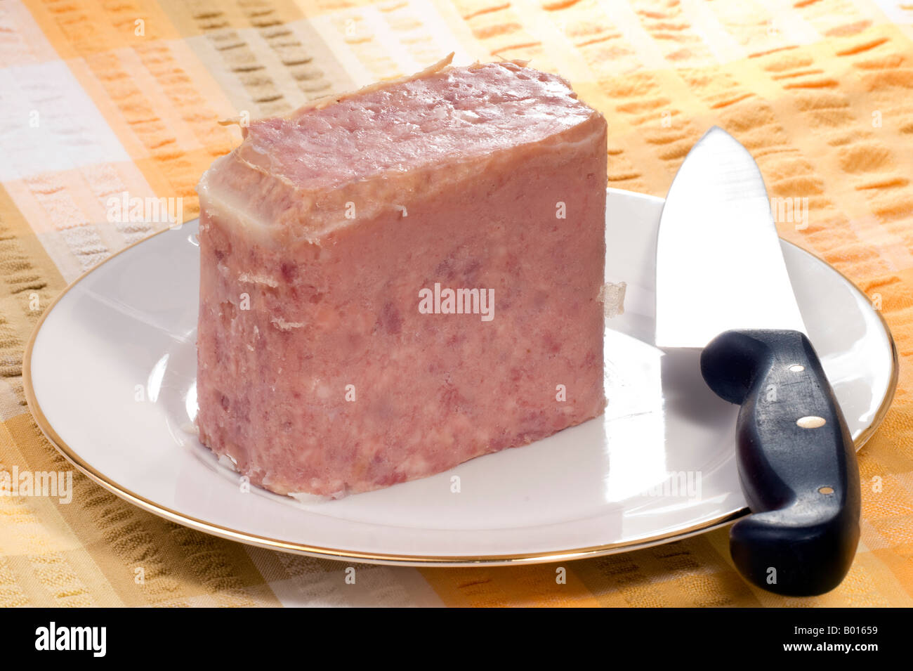 Frühstücksfleisch und ein Messer auf einem weißen Teller Stockfoto