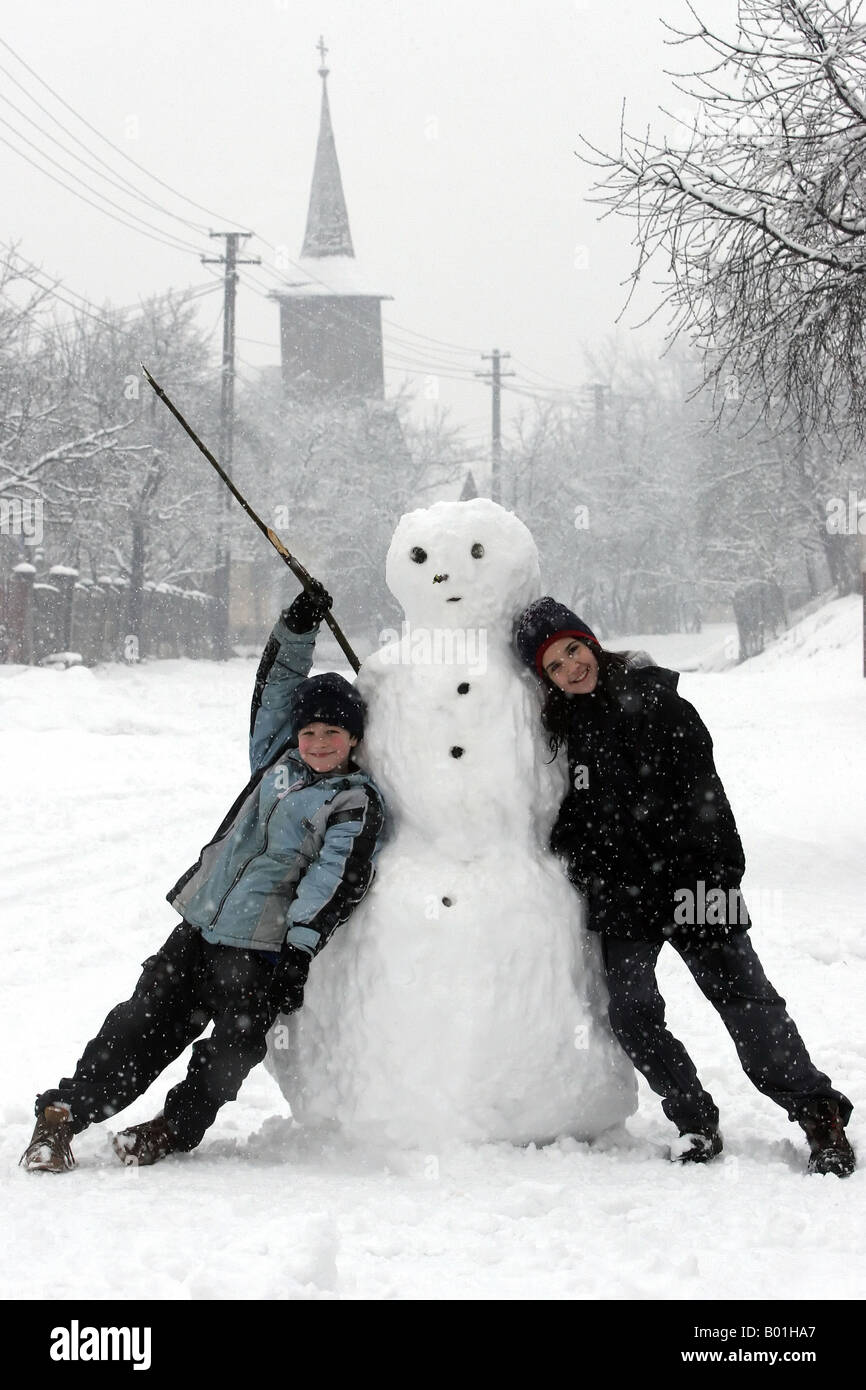 Jungen und Mädchen mit einem Schneemann Stockfoto