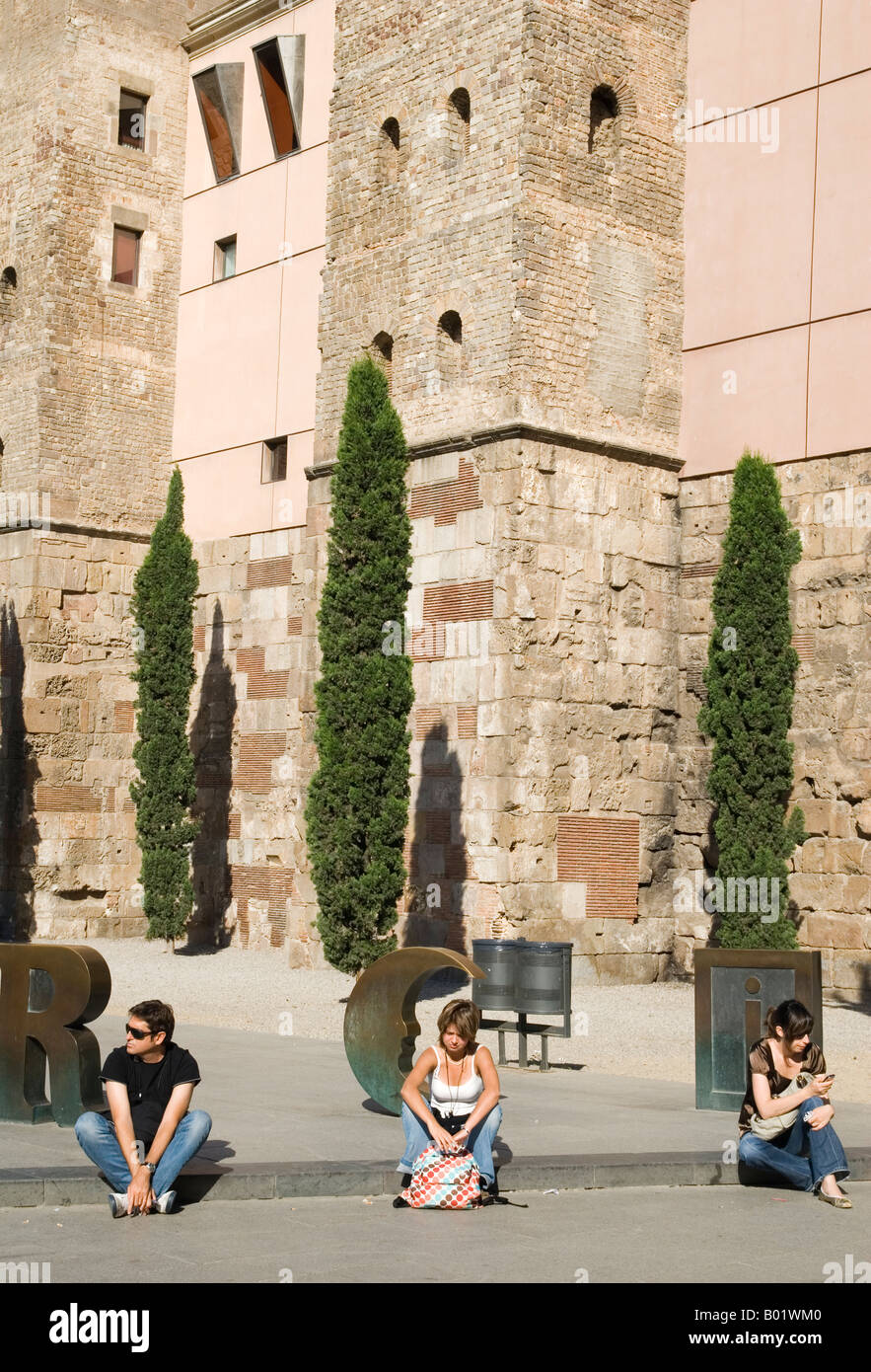 Drei junge Leute sitzen gleichmäßig Vor einigen Bronze Buchstaben in Placa Nova spaced - Rechtschreibung Barcino - der alte Name für Barcelona, Spanien Stockfoto