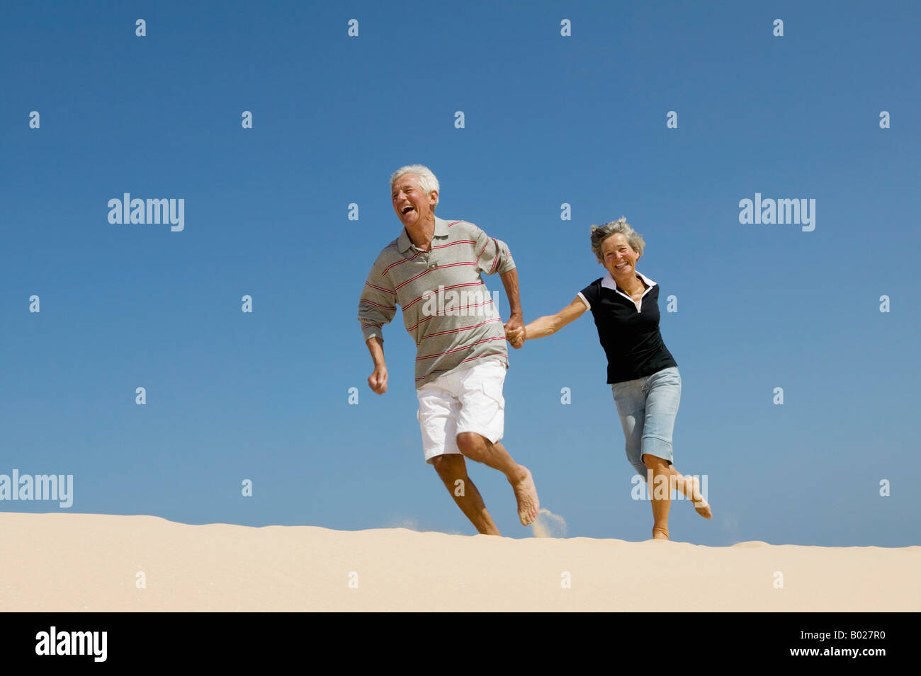 älteres paar laufen hand in hand am Strand Stockfoto