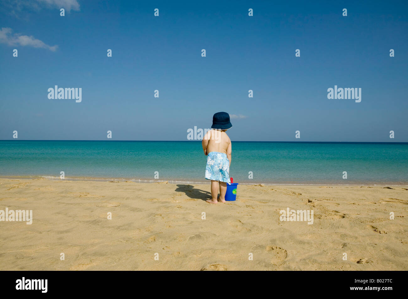 Heckansicht des Kleinkind stehen am Strand mit Eimer Stockfoto