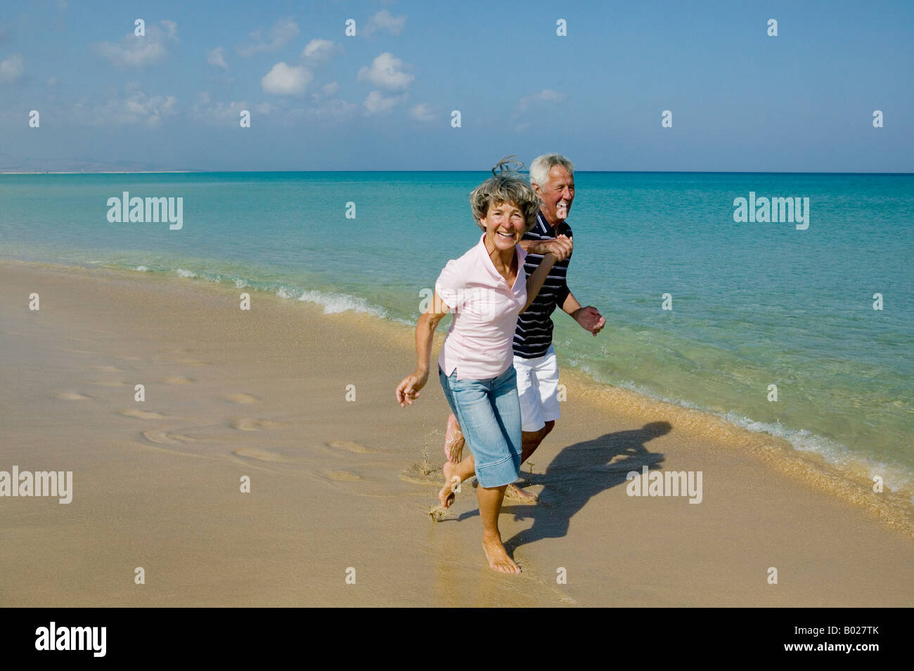 älteres paar Strand entlang laufen hand in hand Stockfoto