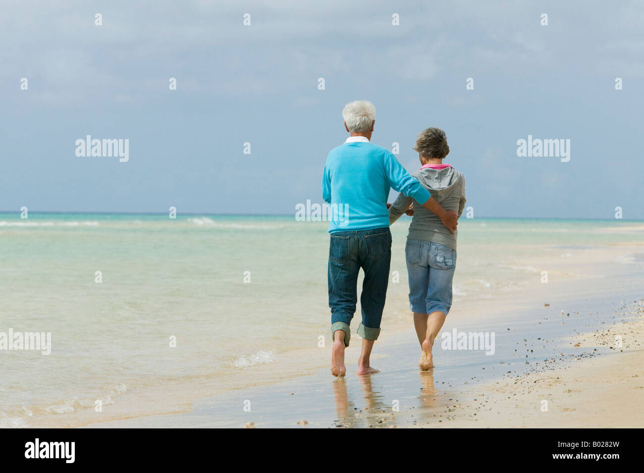Heckansicht des reifes Paar Strand entlang spazieren Stockfoto