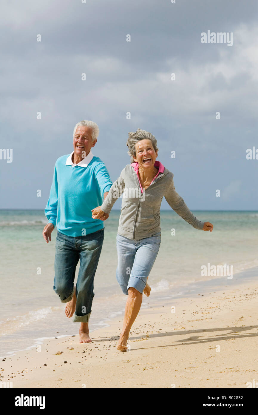 älteres paar laufen Hand in Hand am Strand Stockfoto