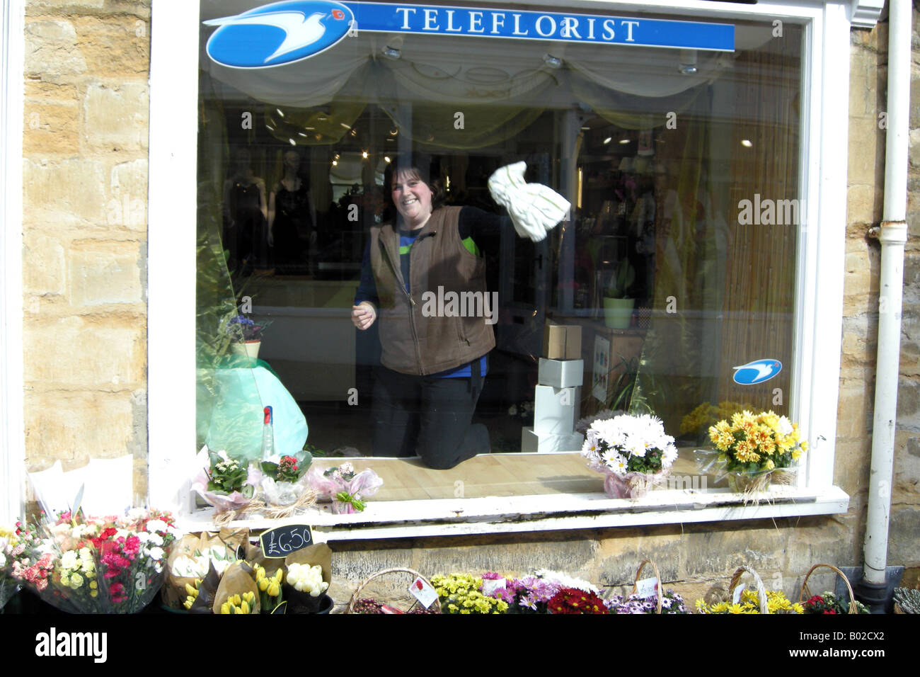 Eine Blume Ladenbesitzer Reinigung ihrer Frontscheibe Stockfoto