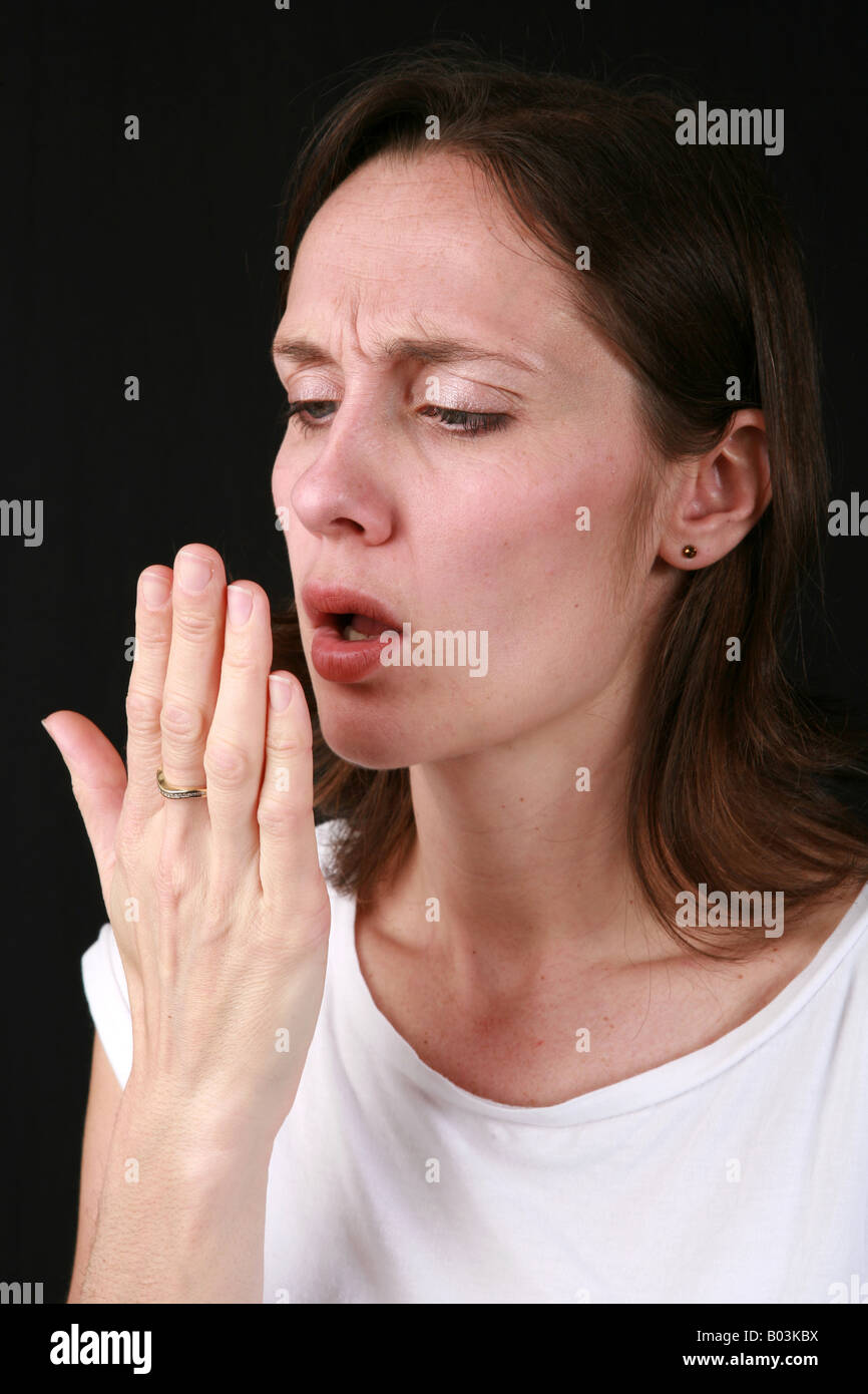 Junge Frau atmet auf Handfläche Mundgeruch Mundgeruch muffiger Geruch schlechte persönliche Mundhygiene Karies wird gesucht Stockfoto