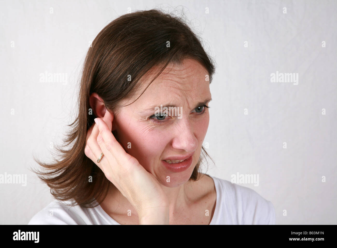 Junge Frau berührt wund schmerzhafte Ohr mit Hand und Fingern unter Ohrenschmerzen leiden oder hören Sie ein lautes Geräusch Stockfoto