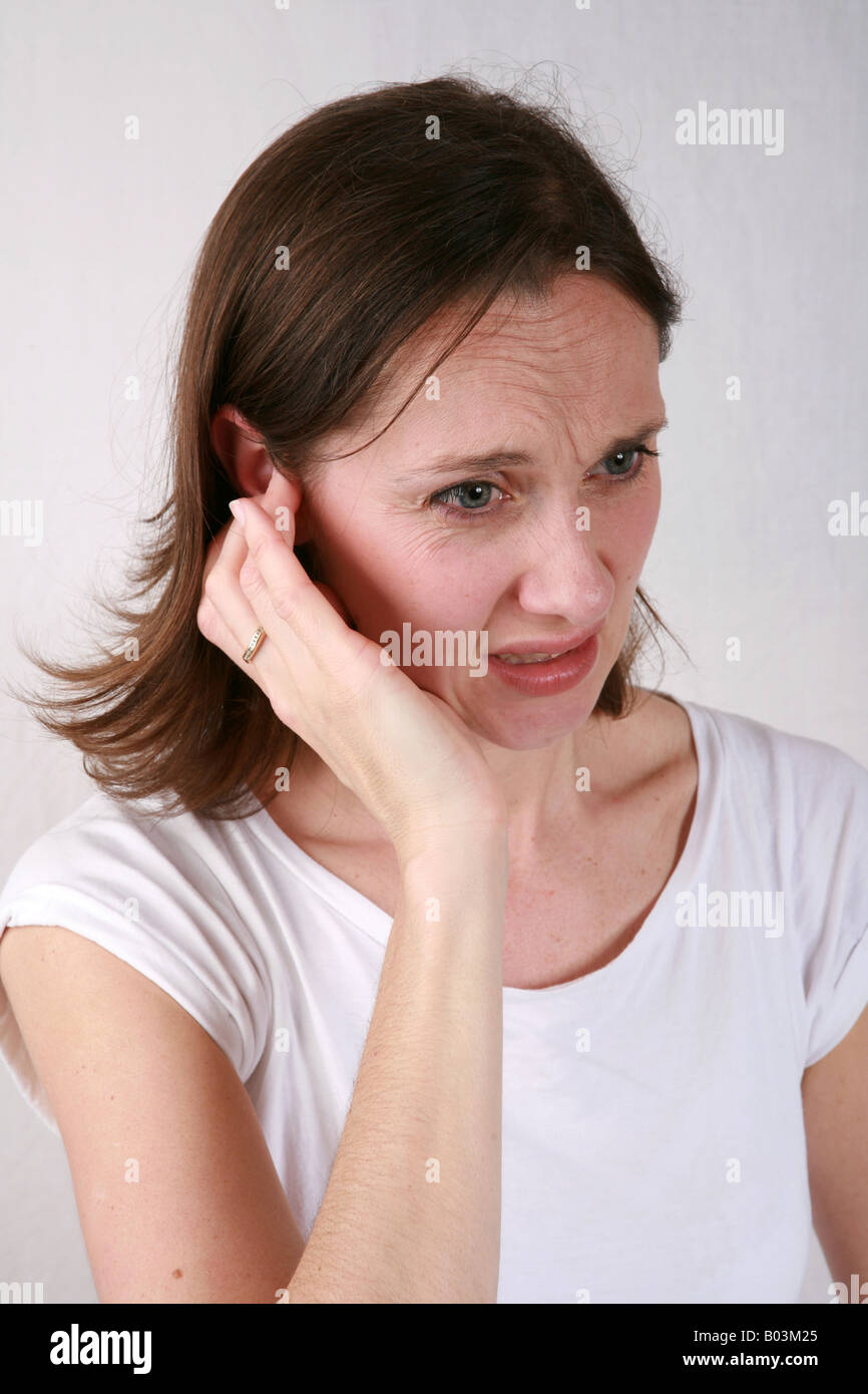 Junge Frau berührt wund schmerzhafte Ohr mit Hand und Fingern unter Ohrenschmerzen leiden oder hören Sie ein lautes Geräusch Stockfoto