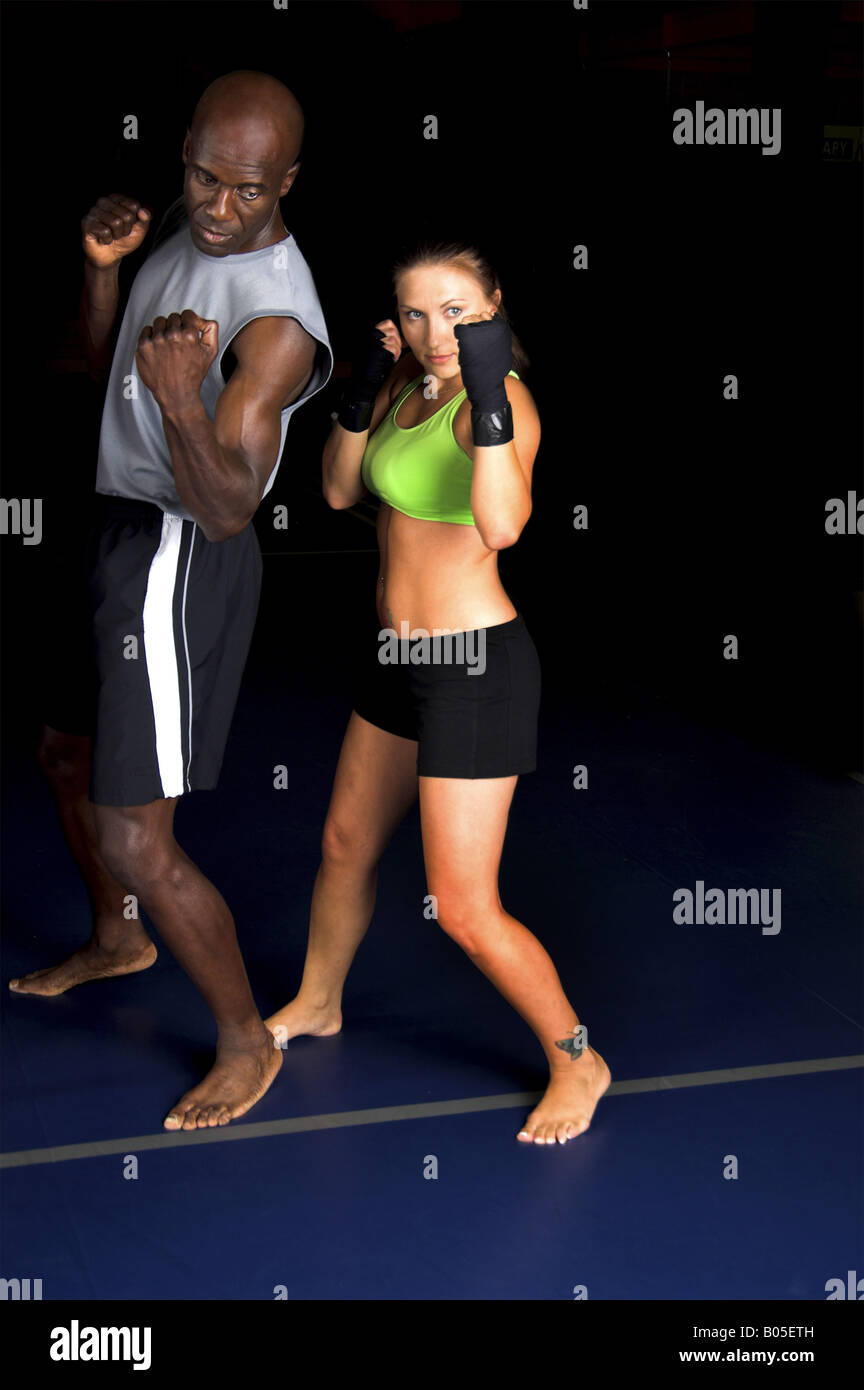 schön, aber gefährliche Frau Kämpfer arbeitet an ihrem oberen Schnitt mit ihrem Trainer in einem Mixed Martial Arts-Turnhalle Stockfoto