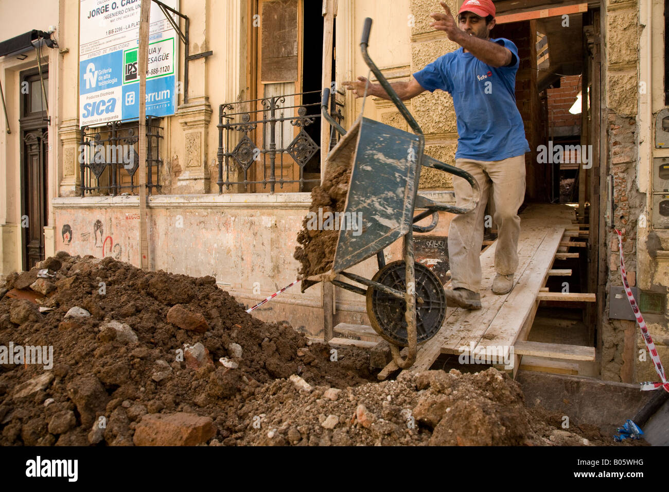 Mann eine Schubkarre von Schmutz zu kippen, während der Renovierung eines Hauses in San Telmo Stockfoto