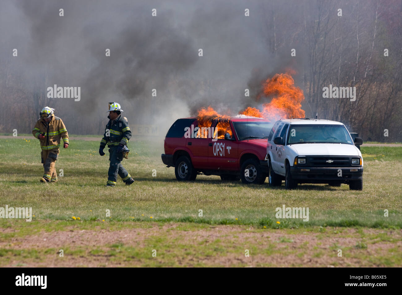 Zwei Feuerwehrleute Fuß entfernt von zwei Fahrzeuge in Brand gesetzt, während einer simulierten Katastrophe Drill am Tweed New Haven Flughafen in den USA. Stockfoto