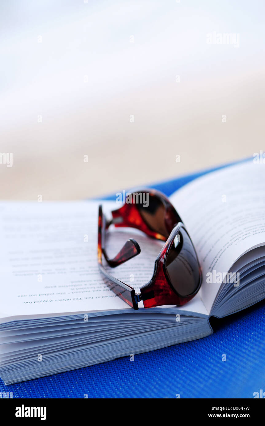 Sonnenbrillen und offenes Buch am Strand Stuhl Sommer Urlaub Konzept Stockfoto