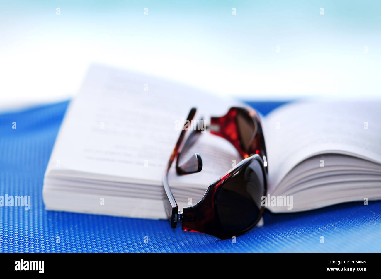 Sonnenbrillen und offenes Buch am Strand Stuhl Sommer Urlaub Konzept Stockfoto