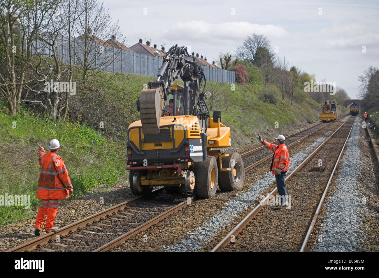 Fremdfirmen führen Fahrer eines Straße-Schiene um seine Bagger auf den Gleisen vor dem Absenken der Stahlschiene Räder zu positionieren. Stockfoto