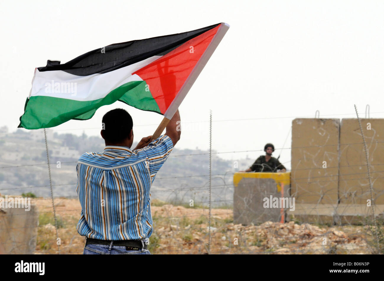 Ein junger Mann während einer Protestaktion gegen die israelische Besatzung in das Dorf von Bilin, Palästina die palästinensische Flagge hissen. Stockfoto