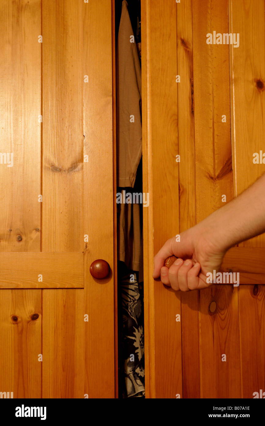 Person, die Schranktür öffnen, Reveal Kleidung innerhalb Stockfoto