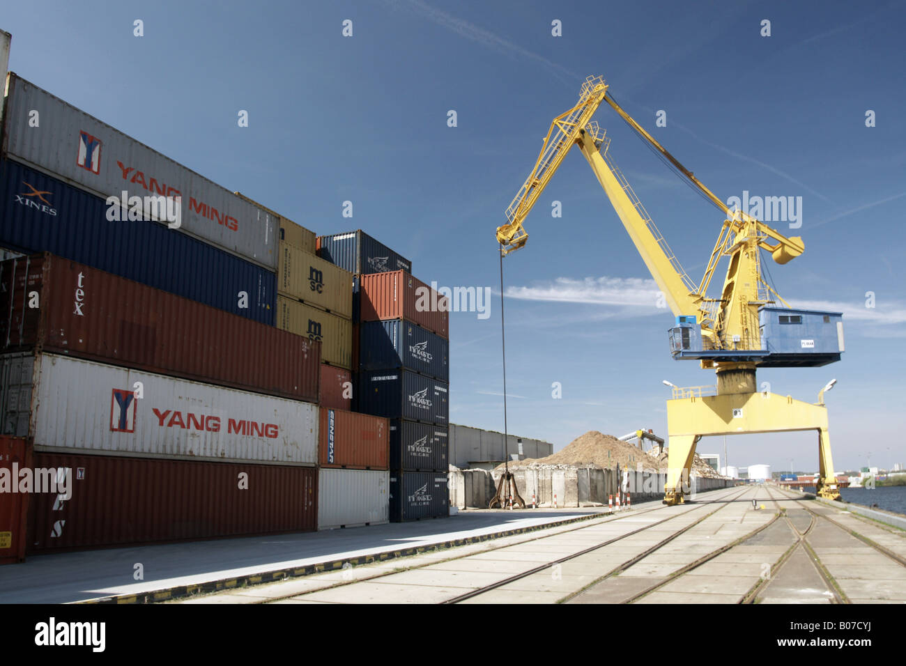 Stapel von Containern mit gelbem Kranich / Frachtcontainer Mit Kran Stockfoto