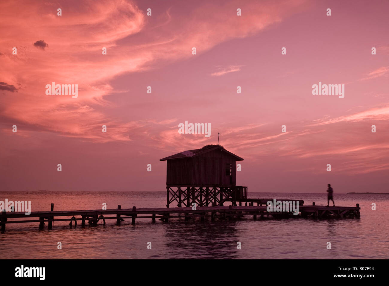 Belize, Tobaco Caye, Mann am Pier bei Sonnenuntergang Stockfoto