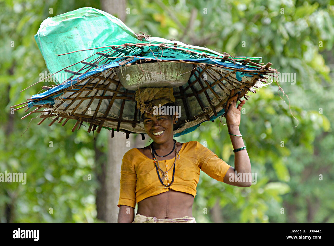 Warli Tribal Frau trägt ein Gefäß und einen Korb auf ihrem Kopf. Ländliche Gesichter Indiens Stockfoto