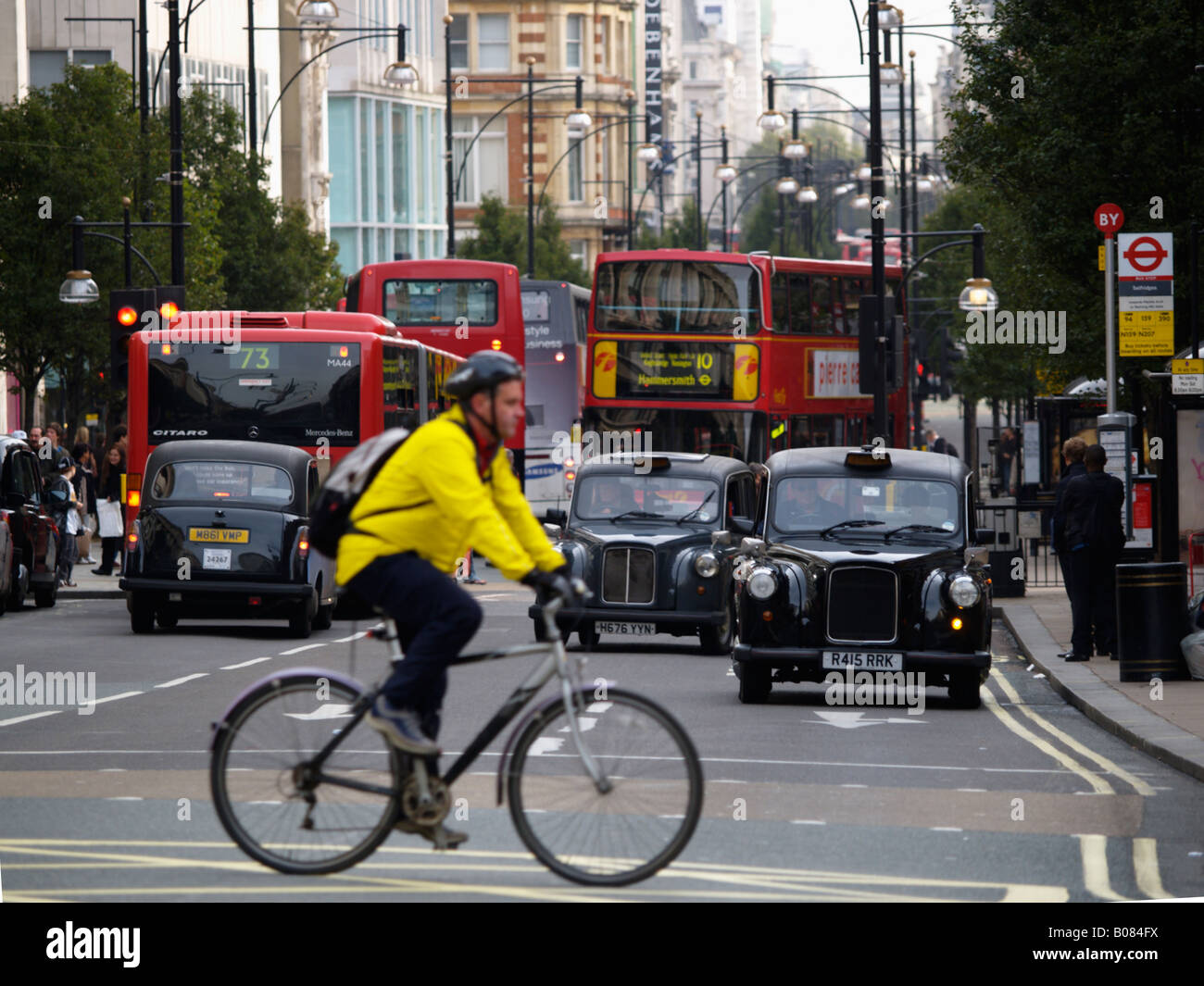 Radfahrer mit gelben Jacke und Helm Kreuzung Reiten auf Oxford Street London UK Stockfoto
