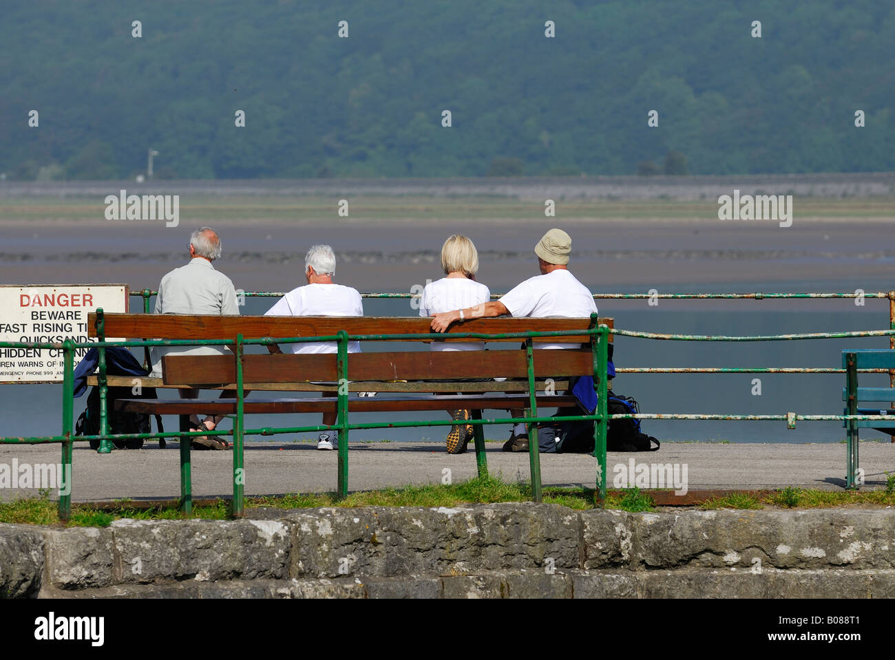 Rückansicht des Menschen sitzen auf einer Bank mit Blick auf die Mündung des Flusses Kent bei Arnside auf Morecambe Bay Stockfoto