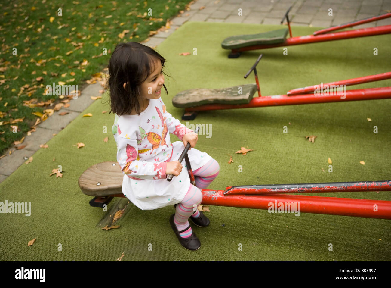 Reiten einer Wippe auf dem Abenteuerspielplatz im Victoria Park, Palmerston North, Neuseeland. Mädchen im Alter von vier Jahren Stockfoto