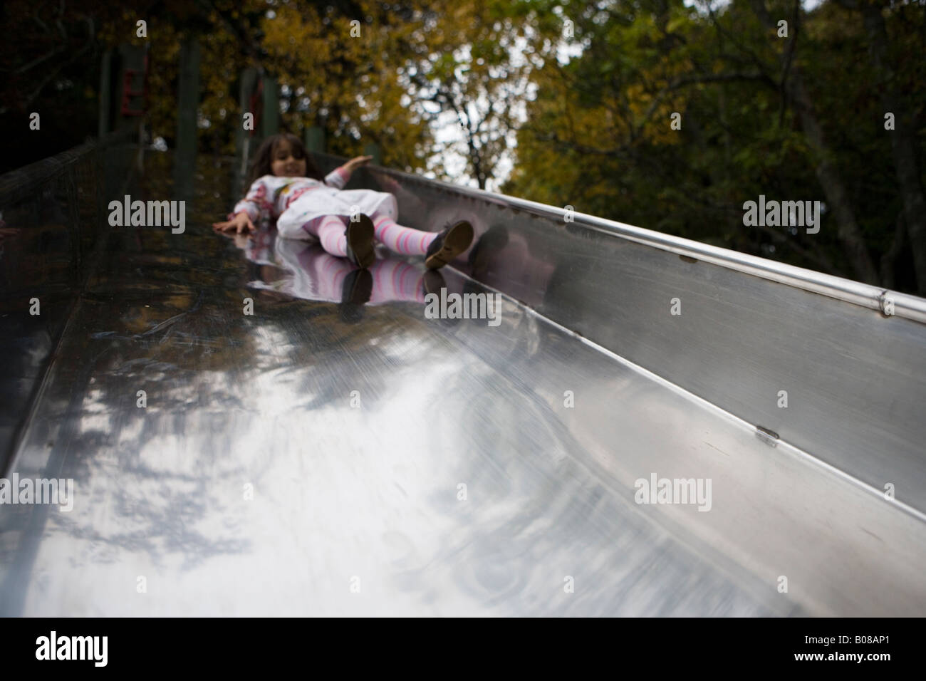 Mädchen im Alter von vier Jahren Folien Stahl Rutsche in einen Abenteuerspielplatz Stockfoto