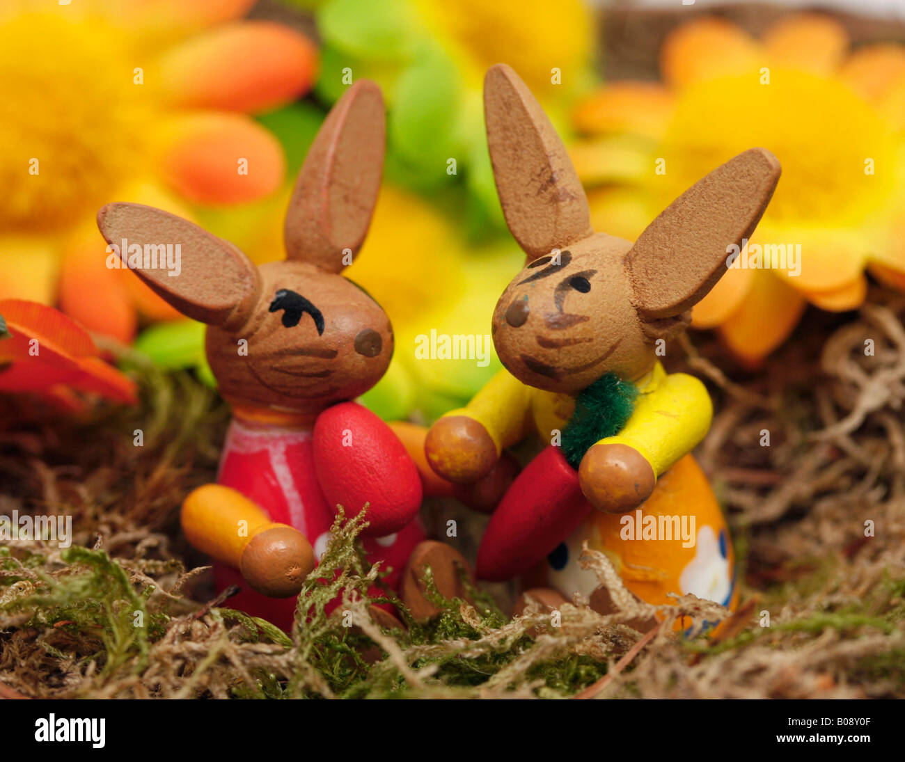 Zwei hölzerne Osterhasen im Korb mit dekorativen Blumen Stockfoto