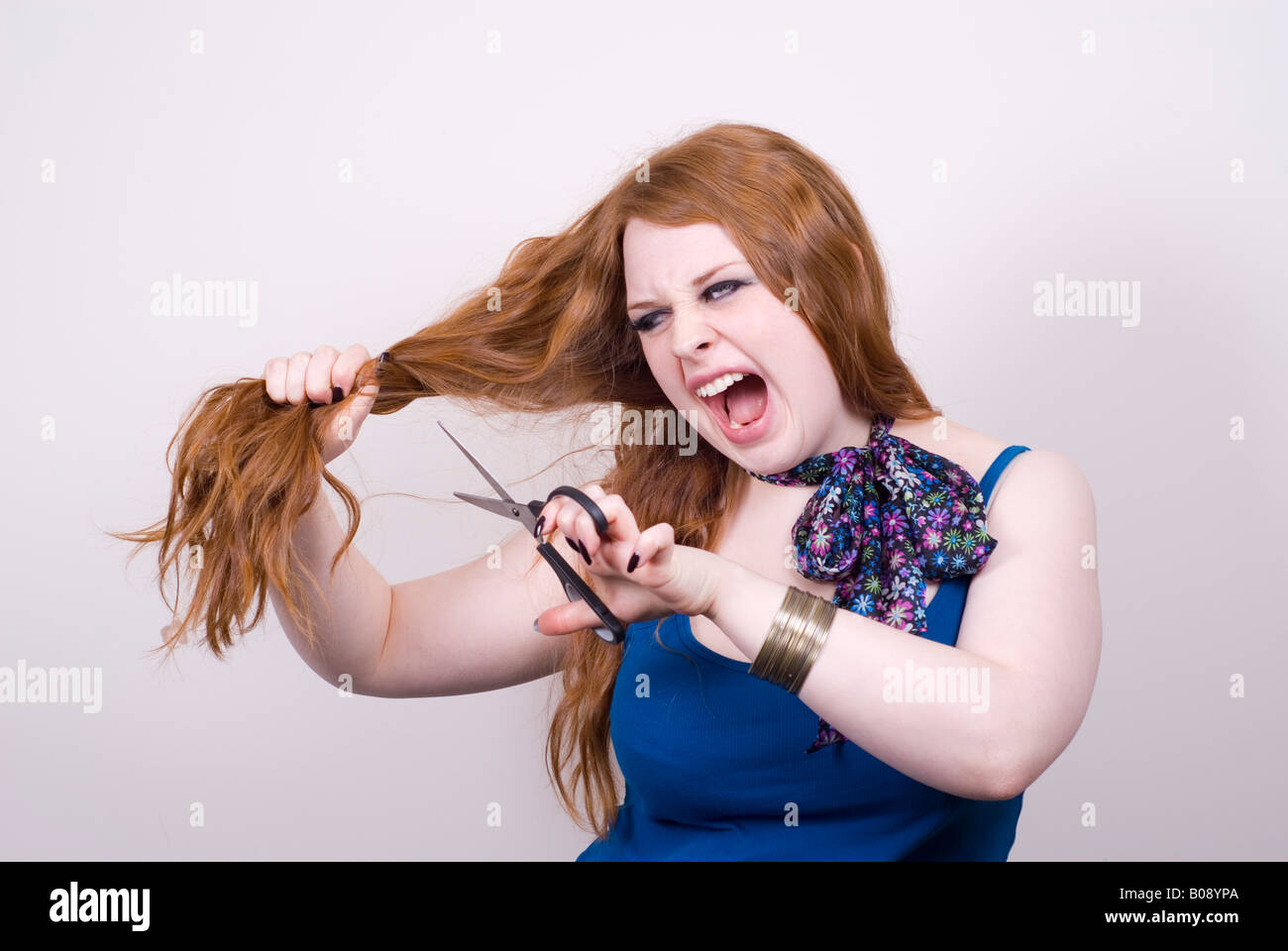 Wütend rothaarige Frau ihr Haar schneiden Stockfoto