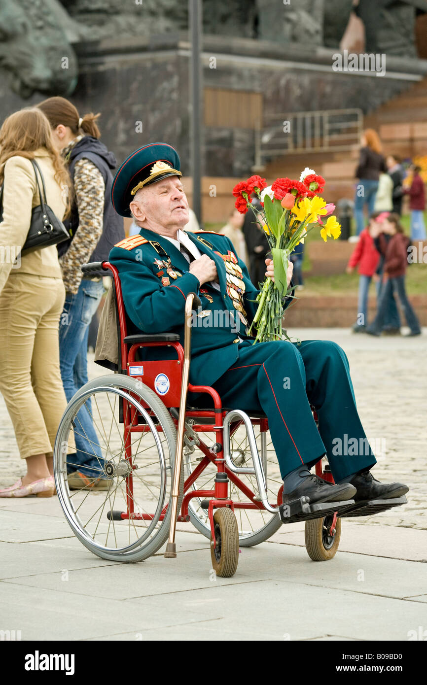 Wheelchaired Rote-Armee-Veteran in Uniform und mit Medaillen tragen Blumen am Tag des Sieges im Park des Sieges, Moskau, Russland Stockfoto