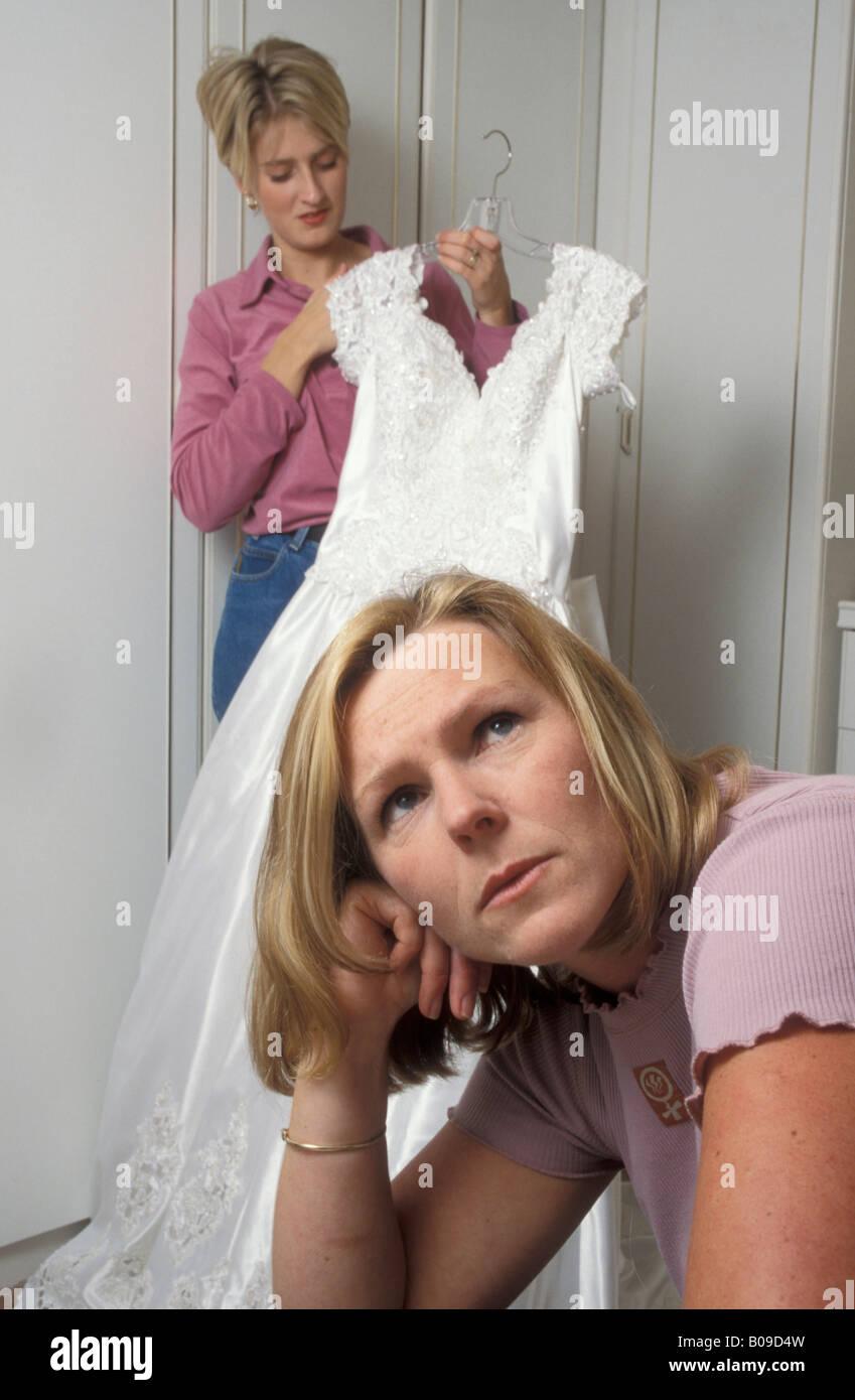 Frau bewundern ihre Hochzeit Kleid während relative Schwester Freund eifersüchtig Stockfoto