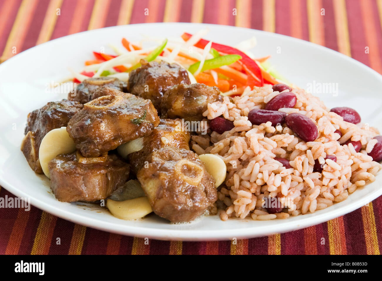 Karibischen Stil Curry serviert mit Reis gemischt mit roten Kidney-Bohnen Gericht begleitet mit Gemüsesalat flachen DOF Ochsenschwanz Stockfoto