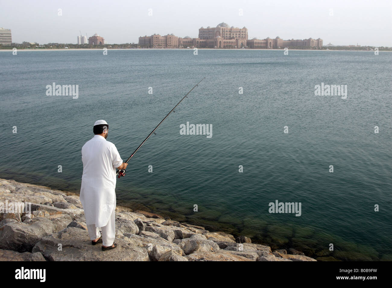 Ein Mann Angeln, das Emirates Palace Hotel im Hintergrund, Abu Dhabi, Vereinigte Arabische Emirate Stockfoto