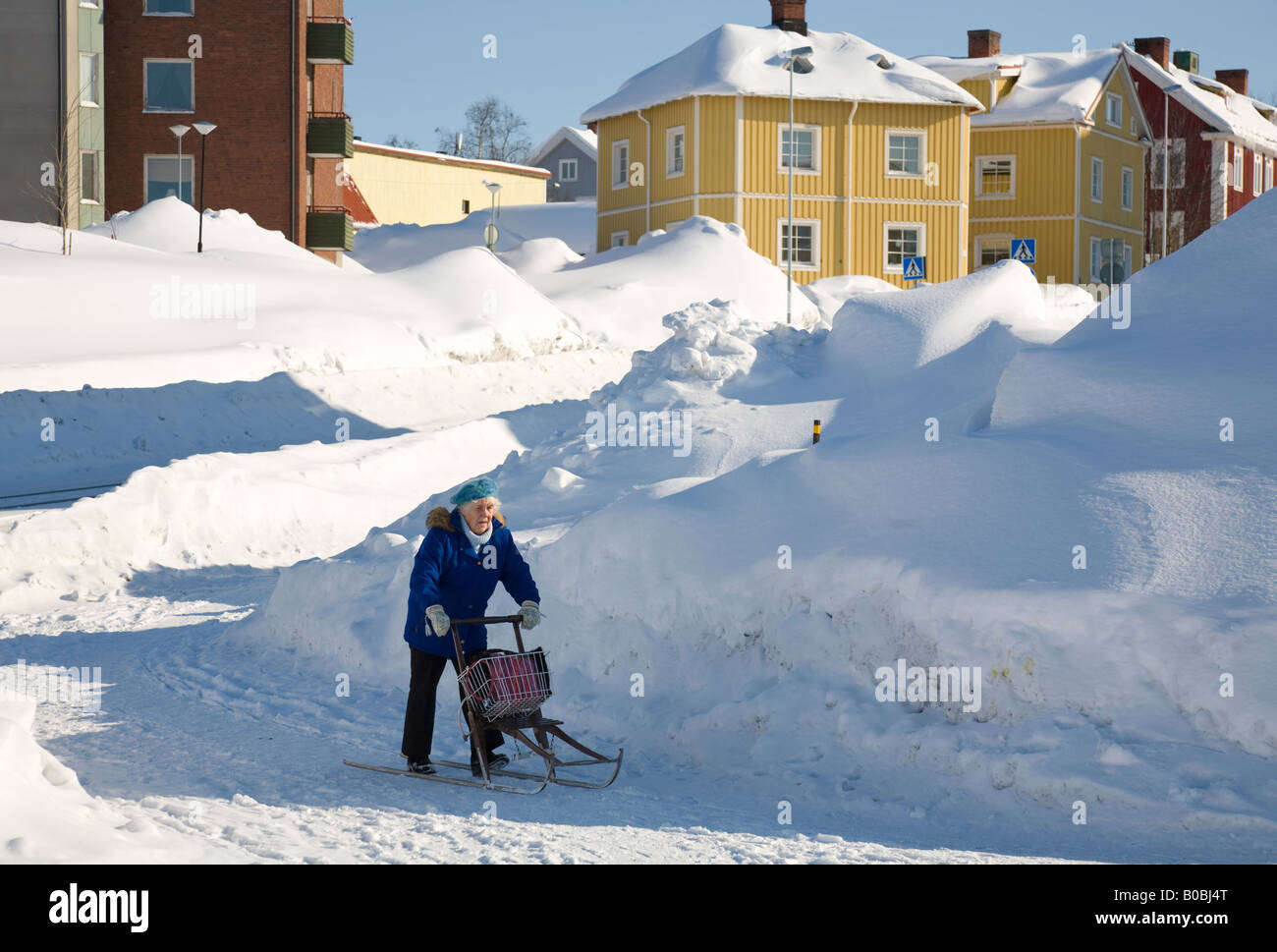Eine ältere Frau Reiten durch den Schnee mit dem Schlitten in das Stadtzentrum von Kiruna / nördlichen Schweden Stockfoto