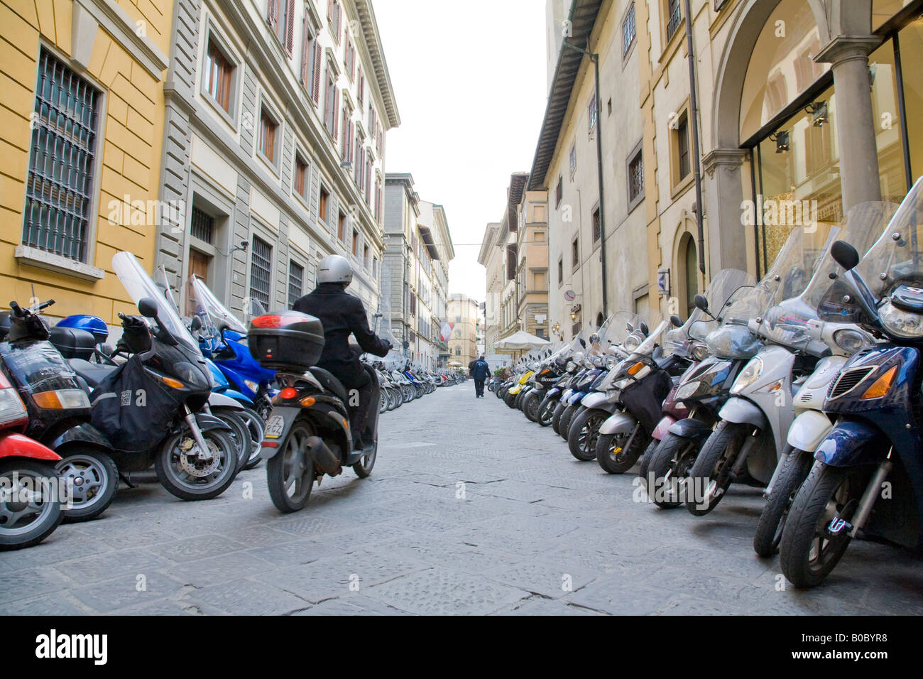 ein motor Radfahrer im Zentrum von Florenz auf einer Straße voller geparkten Motorräder Stockfoto