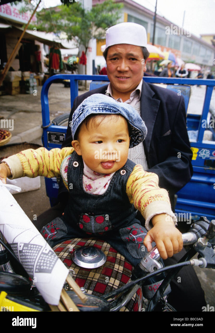 Muslimischen Hui Mann mit seinem Sohn auf dem Motorrad in Lin Xia, Provinz Gansu, ein Silk Road town Stockfoto