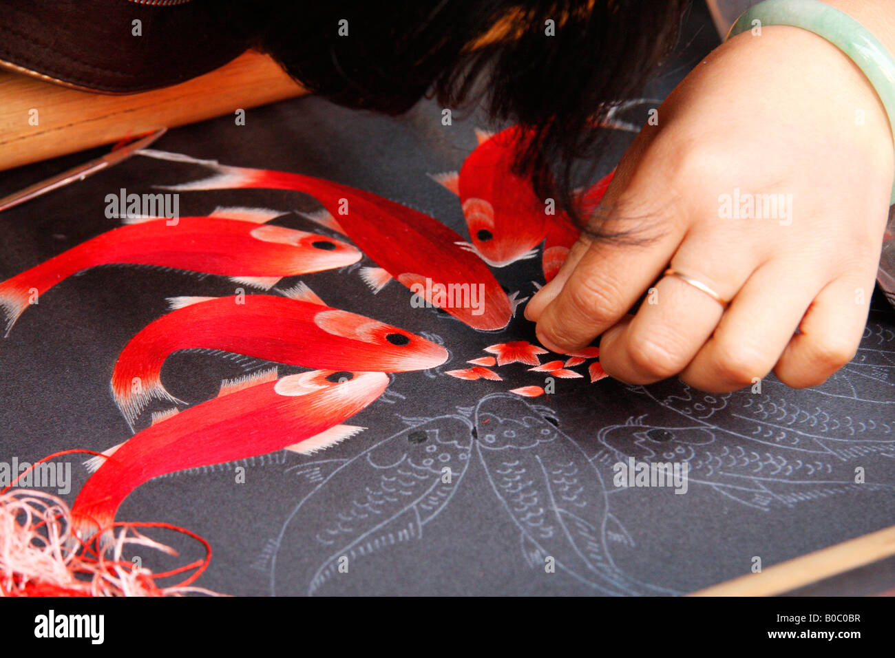 Geschickte Hände einer chinesischen Frau macht eine sehr feine Seidenfaden Stickmuster von Fischen. China Stockfoto