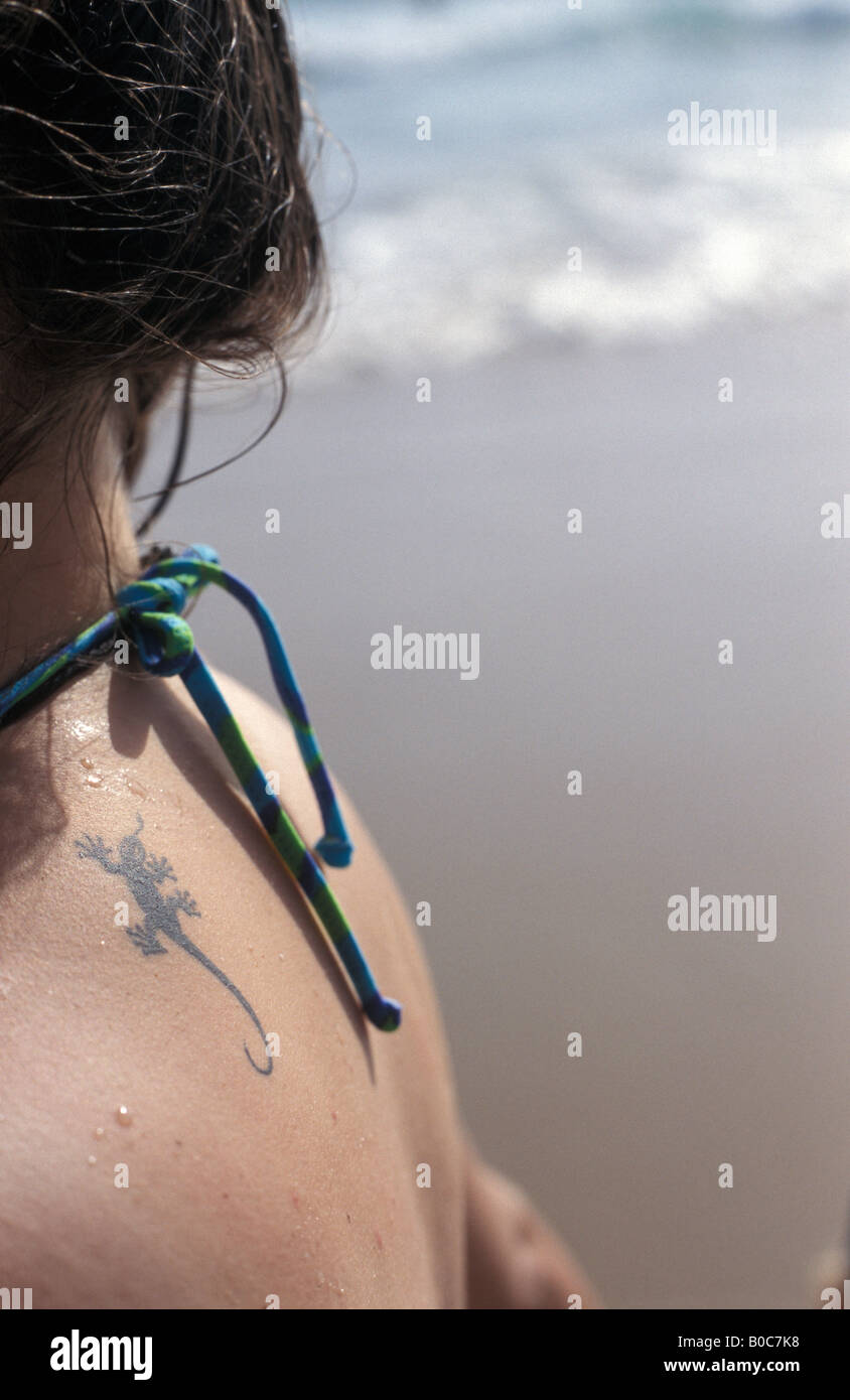 Junge Frau mit Eidechse Tattoo am Strand Stockfoto