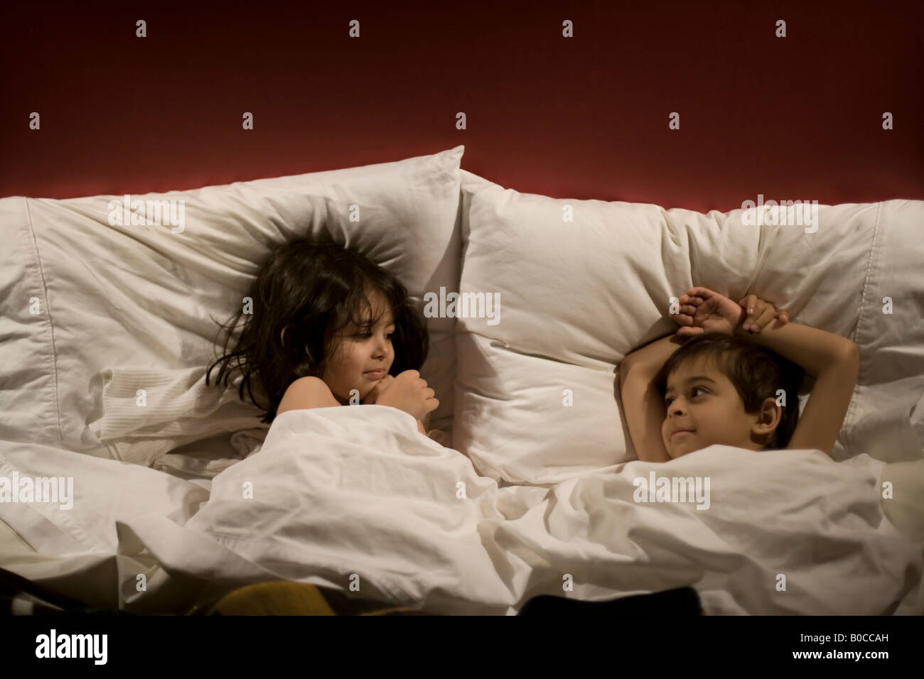 Bruder im Alter von sechs und Schwester im Alter von vier nehmen über ihre Eltern s-Doppelbett Stockfoto