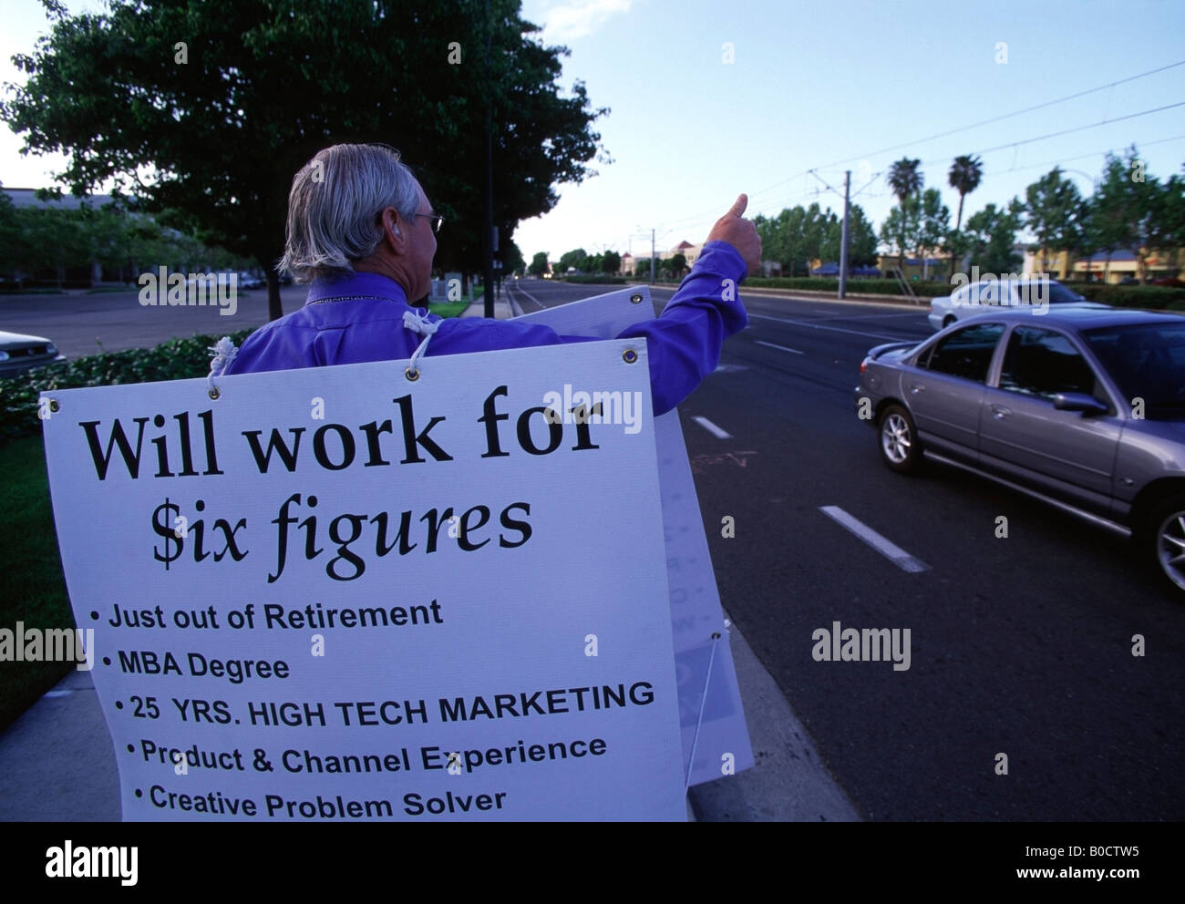 Arbeitslose, ehemalige Marketingleiterin steht an einer Straßenecke im Silicon Valley hält eine Sandwichplatte Werbung selbst. Stockfoto