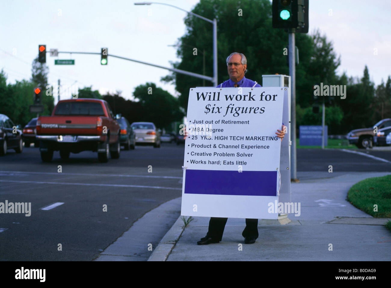 Arbeitslose, ehemalige Marketingleiterin steht an einer Straßenecke im Silicon Valley hält eine Sandwichplatte Werbung selbst. Stockfoto