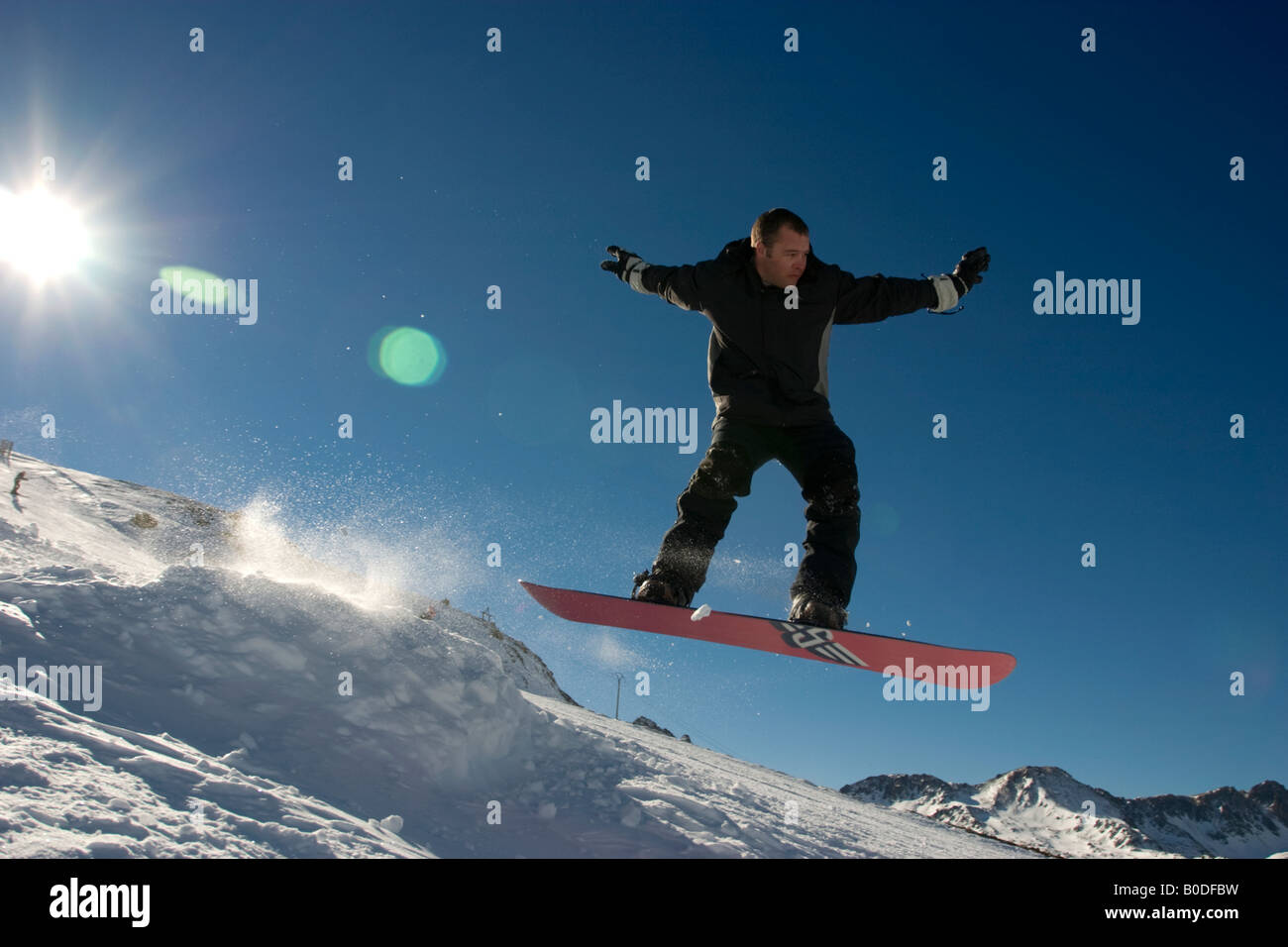 Snowboarder springt gegen blauen Himmel Stockfoto