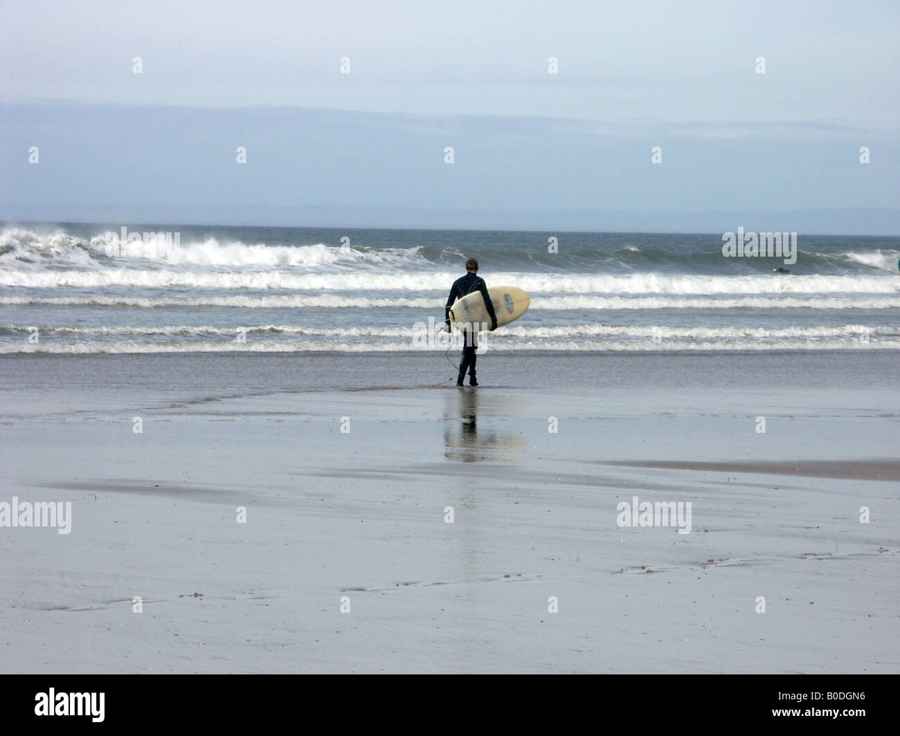 Surfer im schwarzen Anzug zu Fuß aus der Brandung Rhossili Bay, Gower, in der Nähe von Swansea, Glamorgan, Wales Stockfoto