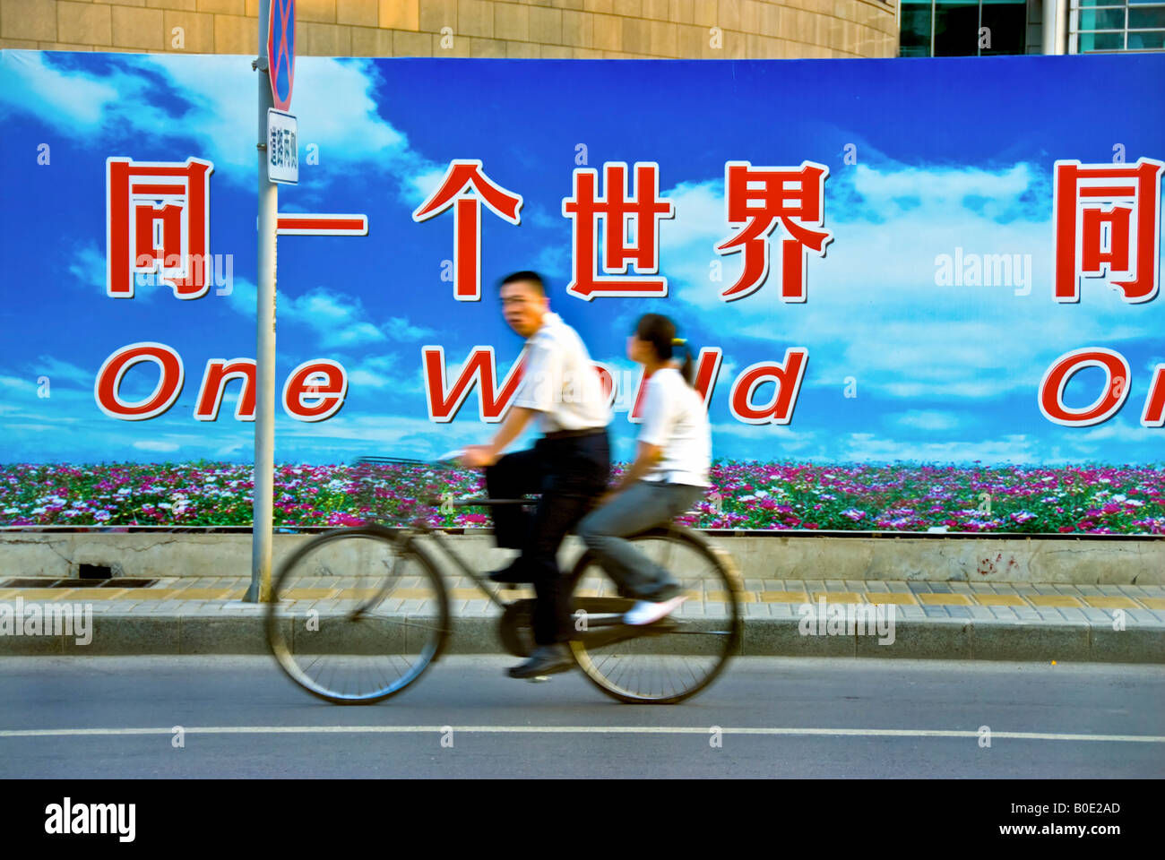Peking China, Straßenszene Paar Radfahren in der Nähe von 'Baustelle' mit großen 'Außenwerbung REKLAMETAFELN' Straßenplakaten in verschiedenen Sprachen, Stockfoto