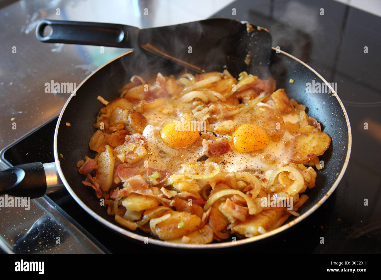 Bratkartoffeln mit Zwiebeln, Spiegelei in der Pfanne Stockfoto