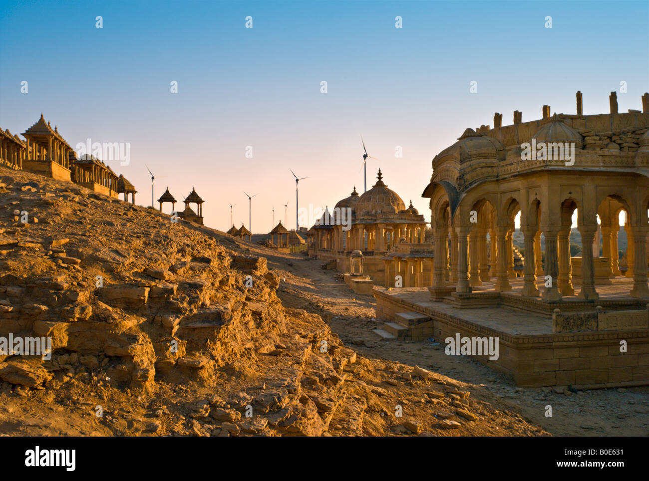 Indien-JAISALMER die alten königlichen Bara Bargh Ehrenmale von Jaisalmer mit moderner Energie produzierenden Windmühlen im Hintergrund Stockfoto