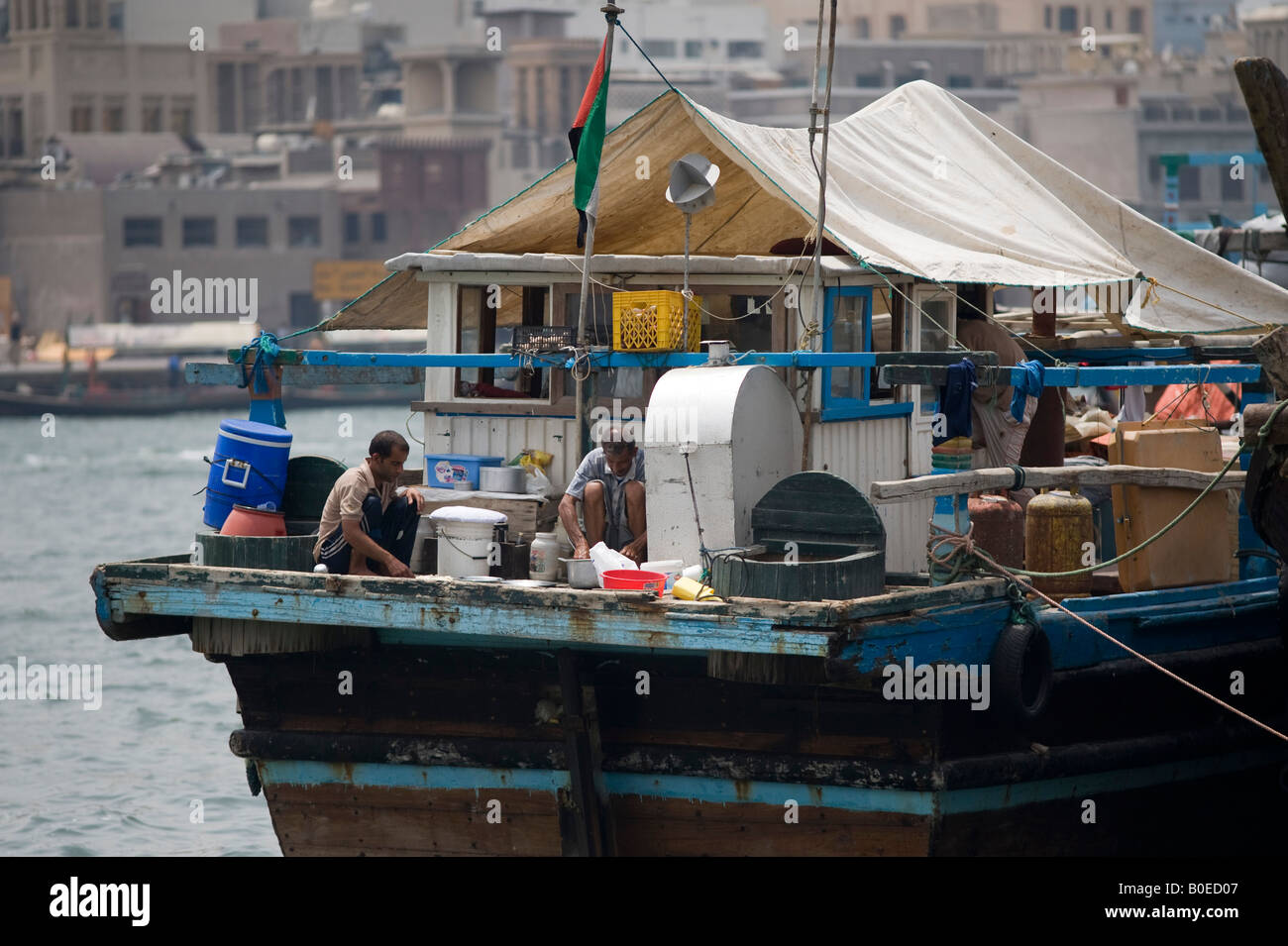 Dubai, Vereinigte Arabische Emirate (VAE). Zwei Besatzungsmitglieder bereiten Sie eine Mahlzeit an Bord einer Dhow auf dem Dubai Creek Stockfoto