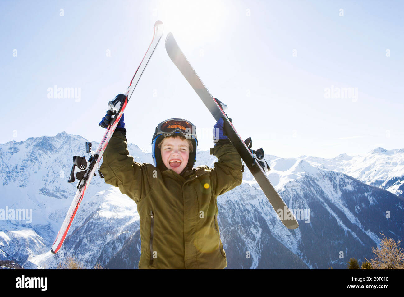 Junge mit Ski über seinem Kopf Stockfoto